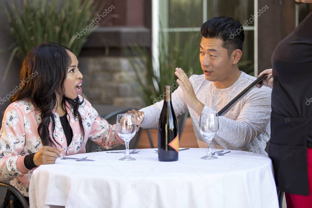 Rude girlfriend complaining to a waitress in a restaurant with an embarrassed boyfriend trying to calm her down.  The image depicts service in the food industry and angry customers.