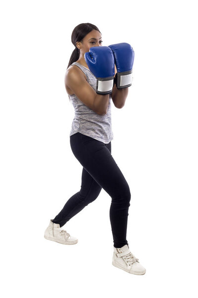 Black female isolated on a white background wearing boxing gloves working out with box aerobics cardio.  She is posing with punches and depicts fitness or self-defense and martial arts.