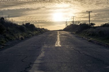 Boş bir yol ya da yarış yolda günbatımı manzara asfalt üzerinde. Yol altın bulutlar doğru yol. Bir yolculuk ve bir arka plan olarak kullanmak için ideal görüntü tasvir. 