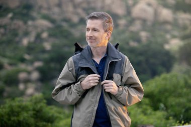 Orta yaşlı bir adam, doğa gezisi sırasında dışarıda aktiviteler yaparak sağlıklı kalıyor. Dağlarda yürüyüş yapıyor ve huzur ve sükunetin tadını çıkarıyor.. 