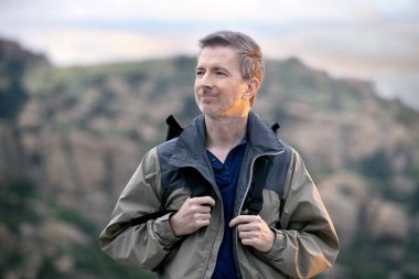 Orta yaşlı bir adam, doğa gezisi sırasında dışarıda aktiviteler yaparak sağlıklı kalıyor. Dağlarda yürüyüş yapıyor ve huzur ve sükunetin tadını çıkarıyor.. 