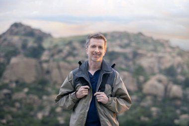 Orta yaşlı bir adam, doğa gezisi sırasında dışarıda aktiviteler yaparak sağlıklı kalıyor. Dağlarda yürüyüş yapıyor ve huzur ve sükunetin tadını çıkarıyor.. 