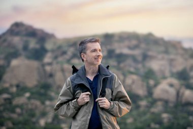 Orta yaşlı bir adam, doğa gezisi sırasında dışarıda aktiviteler yaparak sağlıklı kalıyor. Dağlarda yürüyüş yapıyor ve huzur ve sükunetin tadını çıkarıyor.. 