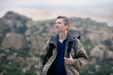 Orta yaşlı bir adam, doğa gezisi sırasında dışarıda aktiviteler yaparak sağlıklı kalıyor. Dağlarda yürüyüş yapıyor ve huzur ve sükunetin tadını çıkarıyor.. 