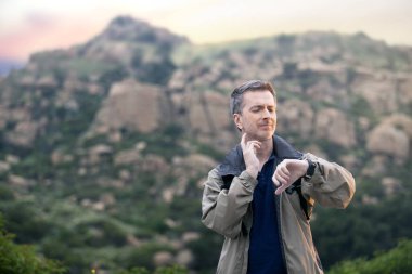 Orta yaşlı bir adam, doğa gezisi sırasında dışarıda aktiviteler yaparak sağlıklı kalıyor. Dağlarda yürüyüş yapıyor ve huzur ve sükunetin tadını çıkarıyor.. 