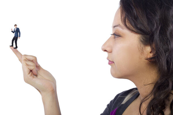 Гигантская женщина держит крошечного бизнесмена в качестве метафоры потери уверенности в себе. Человек чувствует себя уязвимым и беззащитным изолированным на белом фоне

