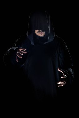 Dumanlı ya da sisli arka planda tarikat lideri gibi görünen koyu renk bornoz giymiş bir adam. Korkunç bir kötü adam gibi görünüyor.