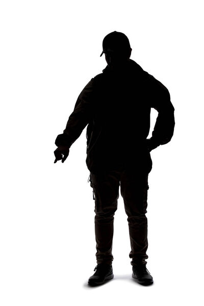 Silhouette of a man wearing a backpack looking like a traveler or hiker trekking.  He is pointing at something