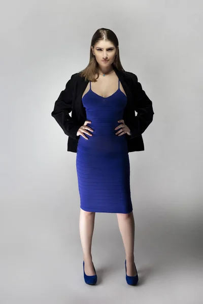 穿着蓝色连衣裙和黑色正式夹克的时装模特装扮成一个穿着性感服装的自信的女商人 在编目风格的工作室拍摄 — 图库照片