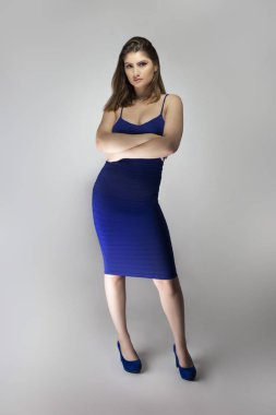 Beyaz bir kadın modelin katalog stili stüdyo fotoğrafı. Donanma ya da kraliyet mavisi bir yaz elbisesi giyiyor. Moda tarzını göstermek için poz veriyor.