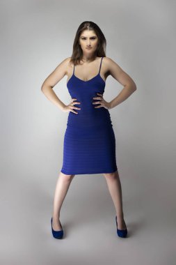 Beyaz bir kadın modelin katalog stili stüdyo fotoğrafı. Donanma ya da kraliyet mavisi bir yaz elbisesi giyiyor. Moda tarzını göstermek için poz veriyor.