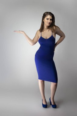 Beyaz bir kadın modelin katalog stili stüdyo fotoğrafı. Donanma ya da kraliyet mavisi bir yaz elbisesi giyiyor. Moda tarzını göstermek için poz veriyor.