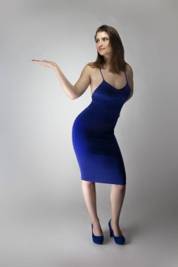 Beyaz bir kadın modelin katalog stili stüdyo fotoğrafı. Donanma ya da kraliyet mavisi bir yaz elbisesi giyiyor. Moda tarzını göstermek için poz veriyor.