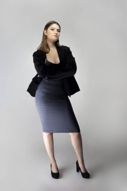 Seksi bir iş kadını gibi davranan, patron ya da menajer gibi görünen bir kadın model. Kıyafeti, iş elbisesi ya da ceketi olan modaya uygun bir kömür mavisi elbise.. 
