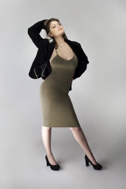 Seksi bir iş kadını gibi davranan, patron ya da menajer gibi görünen bir kadın model. Kıyafeti, iş elbisesi ya da ceketi olan kahverengi ya da ten rengi bir elbise.. 