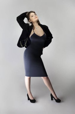 Seksi bir iş kadını gibi davranan, patron ya da menajer gibi görünen bir kadın model. Kıyafeti, iş elbisesi ya da ceketi olan modaya uygun bir kömür mavisi elbise.. 