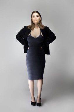 Seksi bir iş kadını gibi davranan, patron ya da menajer gibi görünen bir kadın model. Kıyafeti, iş elbisesi ya da ceketi olan modaya uygun bir kömür mavisi elbise.. 