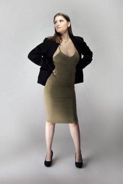 Seksi bir iş kadını gibi davranan, patron ya da menajer gibi görünen bir kadın model. Kıyafeti, iş elbisesi ya da ceketi olan kahverengi ya da ten rengi bir elbise.. 