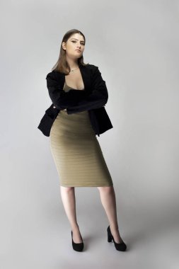 Seksi bir iş kadını gibi davranan, patron ya da menajer gibi görünen bir kadın model. Kıyafeti, iş elbisesi ya da ceketi olan kahverengi ya da ten rengi bir elbise.. 