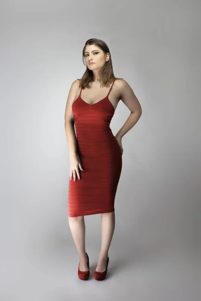 Catalog style studio shot of a Caucasian female fashion model wearing a wine or rose red summer dress.  She is posing to show trendy style of the outfit or clothing