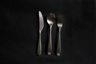 Siyah arka planda bıçak, çatal ve kaşık.