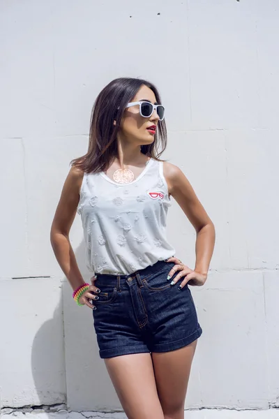 Girl brunette in summer in the park with resting in shorts and a white blouse  background fashion lifestyle, gentle look. Sensual make-up, tanned skin  bright red lipstick. In sun glasses.