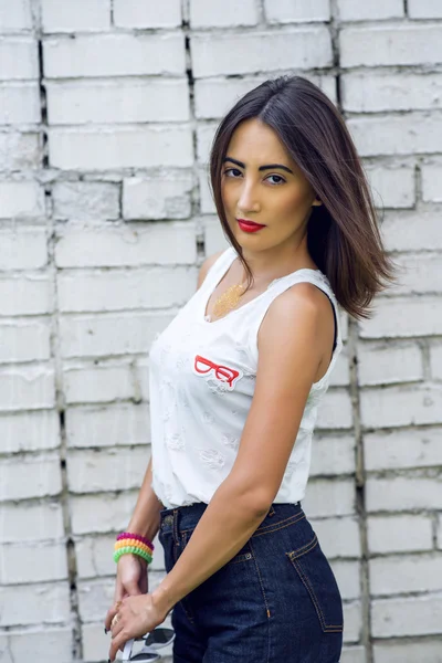 Chica morena en verano en el parque con descanso en pantalones cortos y blusa blanca en el estilo de vida de moda de fondo, aspecto suave. Maquillaje sensual, piel bronceada lápiz labial rojo brillante. Retrato de mujer . — Foto de Stock