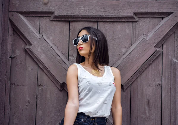 Fille brune dans un parc en été reposant chemisier blanc sur le fond de clôture en bois, mode de vie, look doux. Maquillage sensuel, peau bronzée et rouge à lèvres rouge vif. Portrait femme — Photo