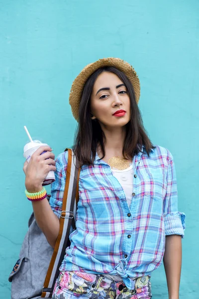 La ragazza in città indossa una camicia sta tenendo un cocktail succo fresco, godendo zaino bruna, abbronzato, trucco sensuale, concetto di ricreazione, viaggi, stile di vita. Giornata estiva. Sullo sfondo di — Foto Stock