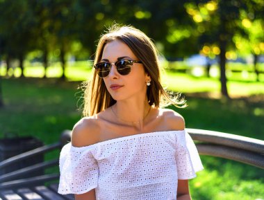 Güzel bir esmer yaz aylarında güneş gözlüğü, beyaz bluz, portresi park, tatil, gençlik kavramı, yaşam tarzı zevk. Tatil keyfi