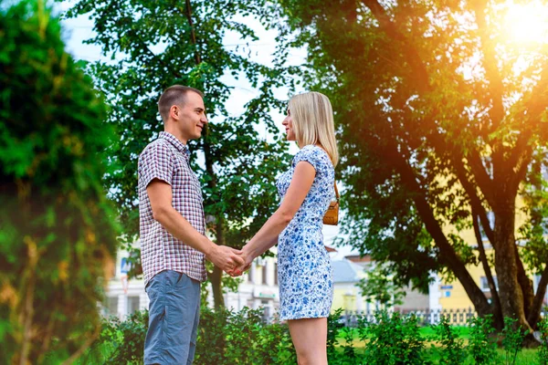 Pareja joven parada en la cinta del parque cogiéndose de las manos, una declaración de amor, un abrazo suave, una familia conceptual, un matrimonio feliz. Estilo de vida en la ciudad. Al aire libre . — Foto de Stock