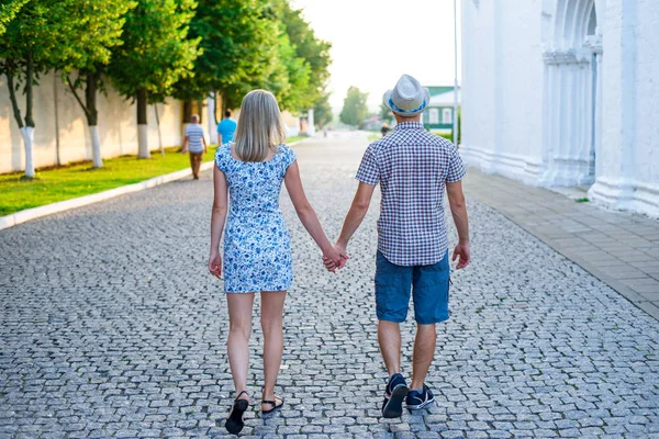 L'homme et la femme sont sur le trottoir de pierre se tenant la main, été en ville, concept de l'événement jeune famille, les jeunes mariés relation complexe. Mode de vie dans la romance. À l'extérieur . — Photo