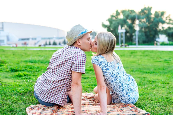 젊은 커플 사랑 개념 가족 이벤트, 관계와 키스 하는 잔디에 앉아 공원에서. 행복 로맨스에 생활양식입니다. 여름날 야외입니다. 밝은  . — 스톡 사진