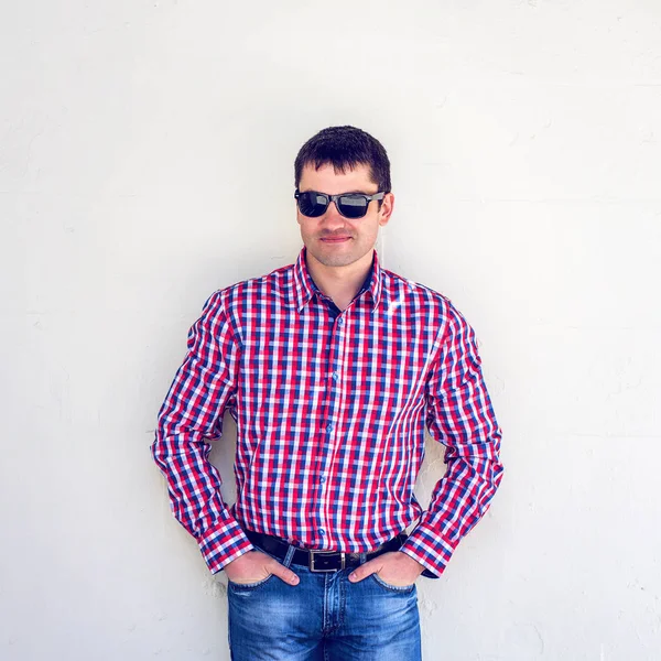 A man stands in the city of a white wall, wearing a shirt in the summer, outdoors resting businessman look important, serious intentions. The concept of emotion, dark glasses. Lifestyle youth on a — Stock Photo, Image