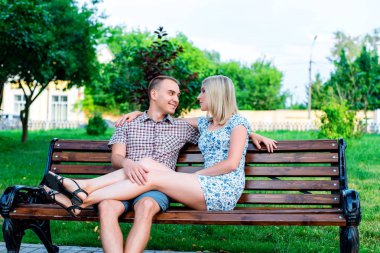 Park sarılma, yaz aylarında şehir, içinde bankta oturan genç modern çift yatay, Aile niteliğine, mutlu bir aile kavramı dinleniyor yaşam tarzı.