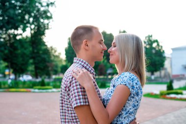 Genç modern çift park, şehir, yatay, doğa dinlenme içinde aile, mutlu bir aile kavramı yaz yaşam tarzı sarılma. Gözlerinin içine bakmaya giderler. Aşk ilanı.