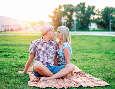 Mutlu bir genç modern çift bir ekose bir parkın içinde oturur, aşk, aşk, mutlu bir aile, bir gençler yaşam tarzı, yeni bir aile hakkında konuşmak Bildirgesi