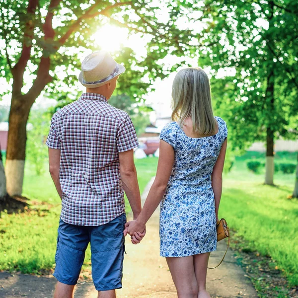 Chlap drží svou přítelkyní za ruku, v létě ve městě siluetu na pozadí úsvitu, koncept vztahů, novomanželé. Životní styl, v létě je kluk s holkou — Stock fotografie