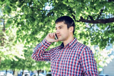 telefonu, akıllı telefon, yaz, işadamı tatil kavramı üzerinde konuşan adam bardaklarda, tişört ve kot pantolon. Şehir bir yaşam tarzı. Park Caddesi.