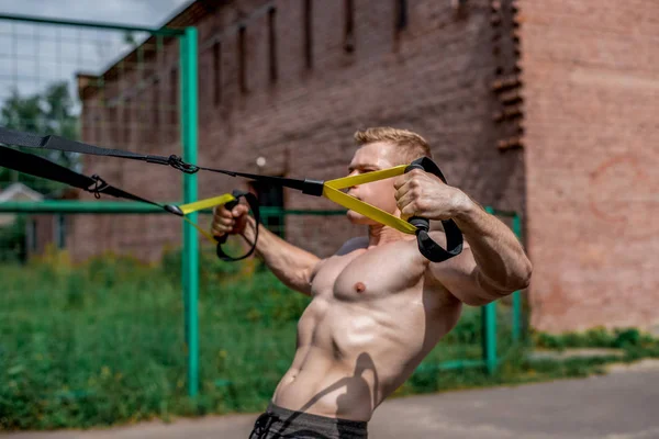 Erkek atlet bir mükemmel eğitim, şehir yaz, eğitim eğitim, döngüler hissediyorum güç ve denge, motivasyon, tabaklanmış deri. Göğüs kas egzersiz. Güneşli bir gün. Bir insanın dayanma gücü