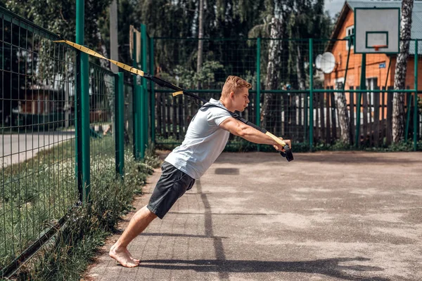 Atlet, açık hava, oyun spor, şehirde, beyaz gömlek, şort, yaz aylarında bir erkekte simülatörü sıkar. Şehirdeki aktif dinlenme.