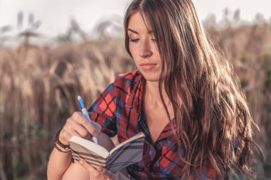 Güzel esmer kız alan, gömlek. Kavram yeni fikirler, not defterinde yazılı. Bir kadın bir defterde yazar. Gazeteci notun bir günlük okur.