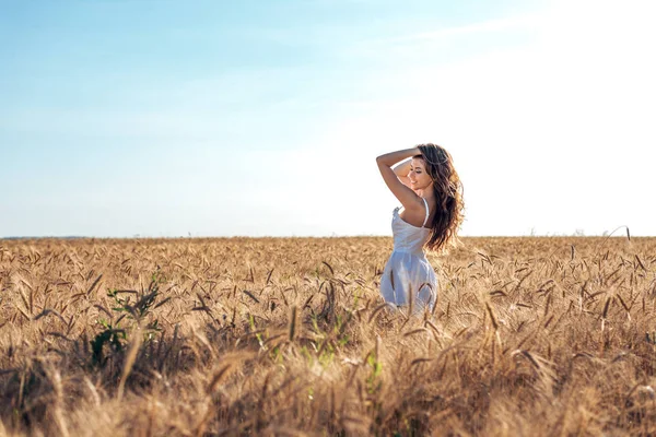 Vackra lycklig kvinna fält, solig eftermiddag, vit klänning. Brunett hår, solbränd hud, begreppet njuter av naturen. Lyckligt leende. Harmoni med vete. — Stockfoto