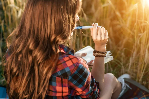 Mooi blij meisje in veld, zonnige dag shirt. Concept nieuwe ideeën, schrijven in notitieblok. genieten van de natuur. Rusten op de lucht. — Stockfoto