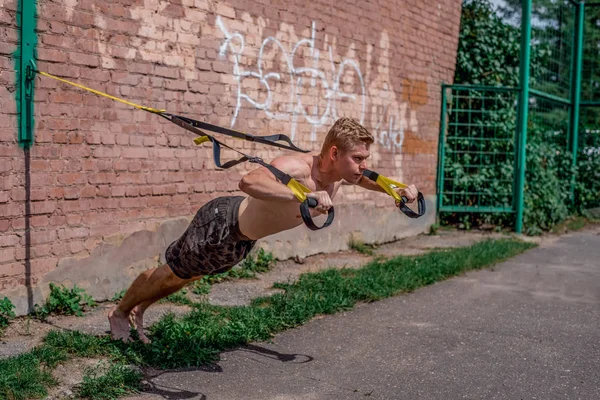 Bir erkek atlet açık hava döngüler içinde tuğla duvardan uzak iterek trenler göğüs, devreye girer. Yaz aylarında, şort ve çıplak bir gövde. Gençlerin sağlıklı bir yaşam tarzı. Spor motivasyon kavramı.