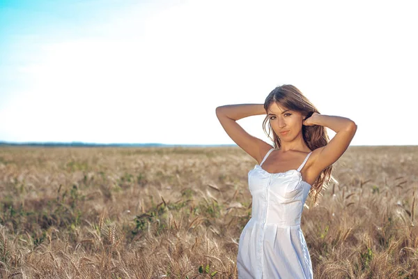 Flicka i vit klänning fält, vete friluftsliv, vacker klänning. Kvinna poserar utomhus i långt hår. Närbild — Stockfoto