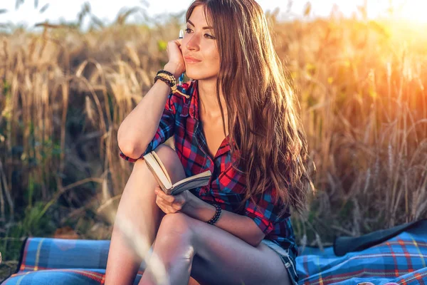Girl sitting in a field shirt, wheat relaxing in nature, beautiful brunette hair. The notepad of idea is dreaming. A student after class. Concept of plans for the future. — Stock Photo, Image