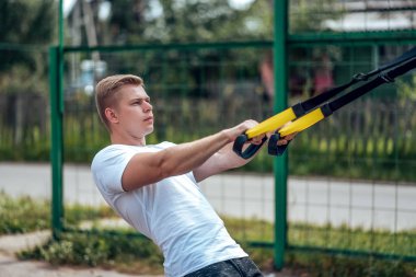 Atlet silah kaslarının geri, en geniş askıları. Bir adam bir atlet, menteşeleri üzerinde nişanlandı. Yaz aylarında zemin sporda. Temiz havada egzersiz. Sağlıklı bir yaşam tarzı kavramı.