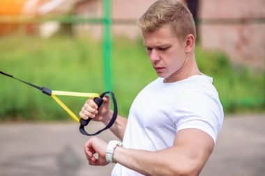 Bir erkek Koç yaz tişört bir darbe, bir şehir doğa ölçer. Atlet saate benziyor. Sağlıklı bir yaşam tarzı kavramı. Temiz havada egzersiz. Pazı için kayış menteşeler.