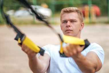 Atlet triceps kol kaslarının kayışlar. Erkek atlet, uğraşan menteşeler, yakın çekim. Arkadaki gücünü konsantrasyon. Temiz havada egzersiz. Sağlıklı bir yaşam tarzı kavramı.